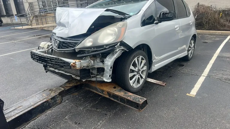 Damaged Honda being recovered by a tow truck after an accident.